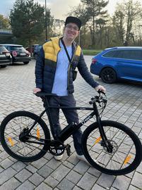 Gewinner Kai mit seinem neuen E-Bike auf dem Parkplatz der Sporthalle An der Düne